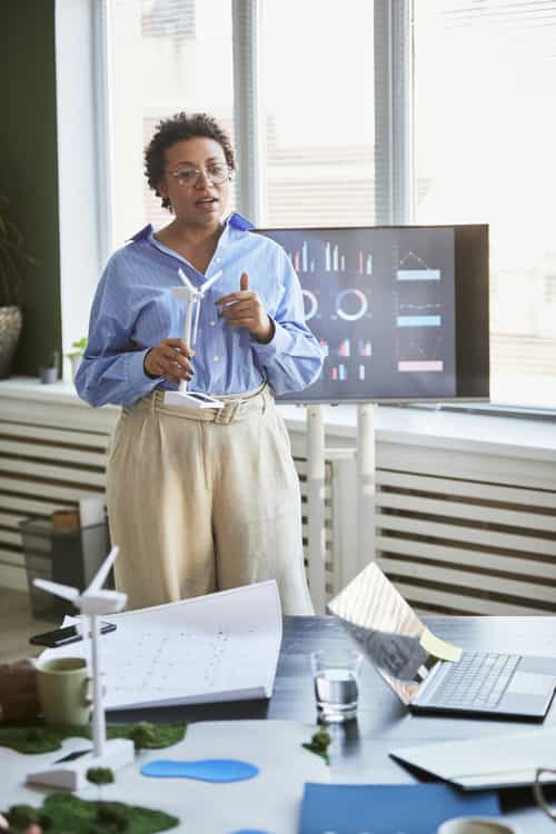 african-young-businesswoman-with-windmill-mockup-talking-about-alternative-energy-presentation