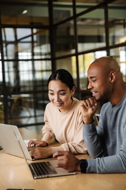 multiethnic-young-female-male-coworkers-sitting-table-working-laptops-office