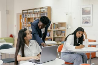 Professor helping student on laptop.