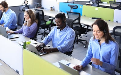 smiling-african-male-call-center-operator-with-headphones-sitting-modern-office-with-collegues-backgroung-consulting-online