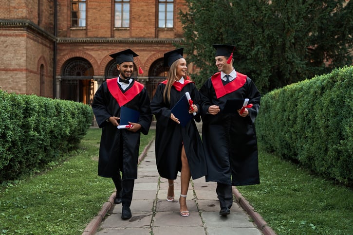 three-gradutes-friends-graduation-gowns-walking-campus